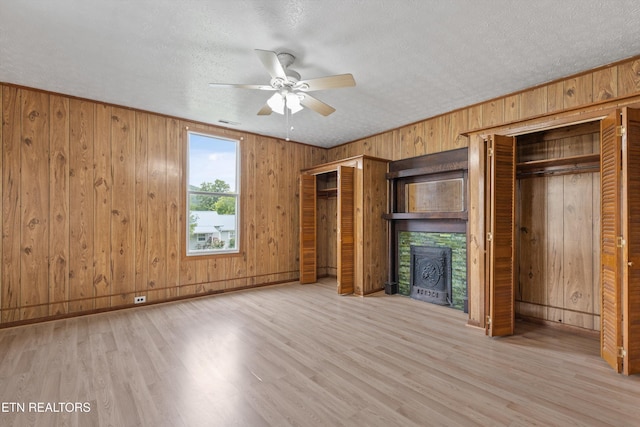 313 W Spring St, Oliver Springs, TN 37840 - unfurnished bedroom with two closets, wood walls, wood finished floors, a textured ceiling, and ceiling fan