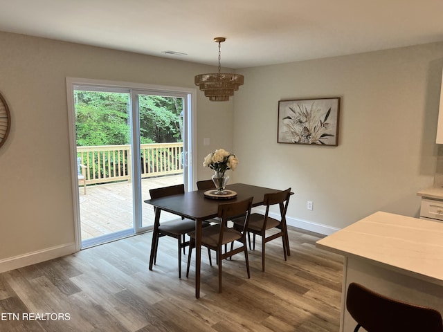 dining space with a chandelier, dark wood-type flooring, and baseboards