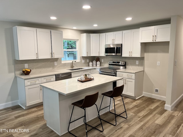 kitchen featuring stainless steel appliances, a sink, white cabinetry, tasteful backsplash, and recessed lighting