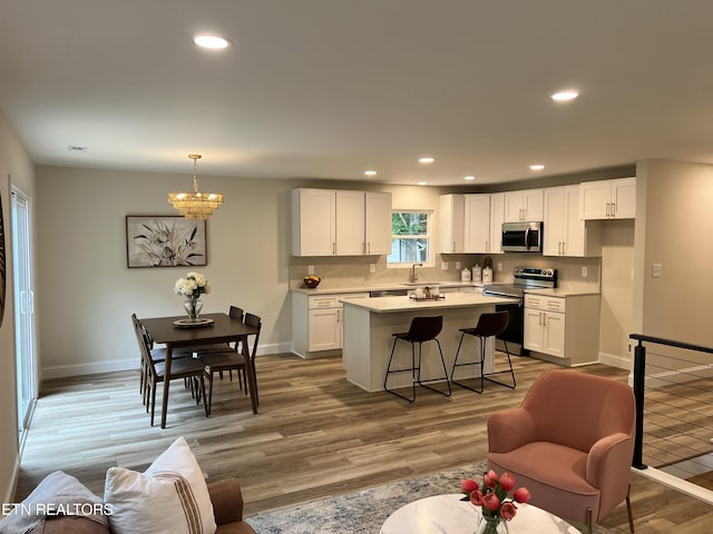 kitchen with appliances with stainless steel finishes, a sink, white cabinetry, light wood-style floors, and light countertops