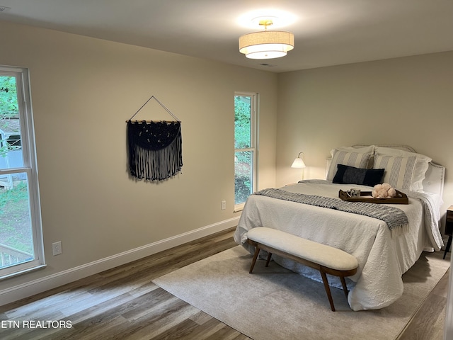bedroom with dark wood-type flooring and baseboards