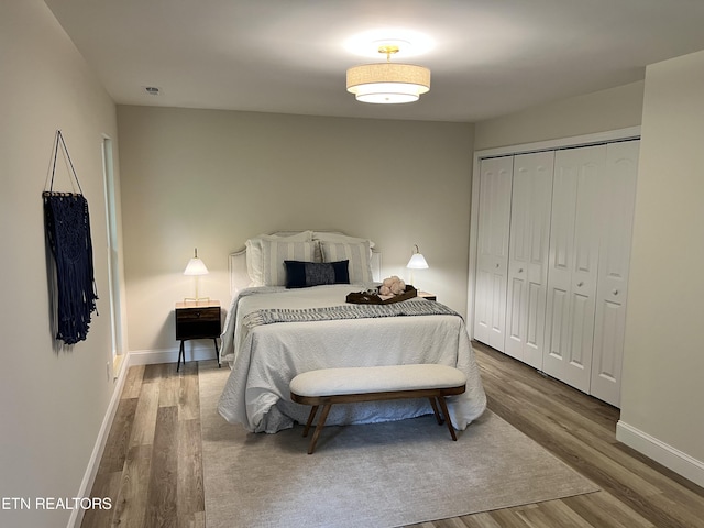 bedroom with wood finished floors, baseboards, and a closet