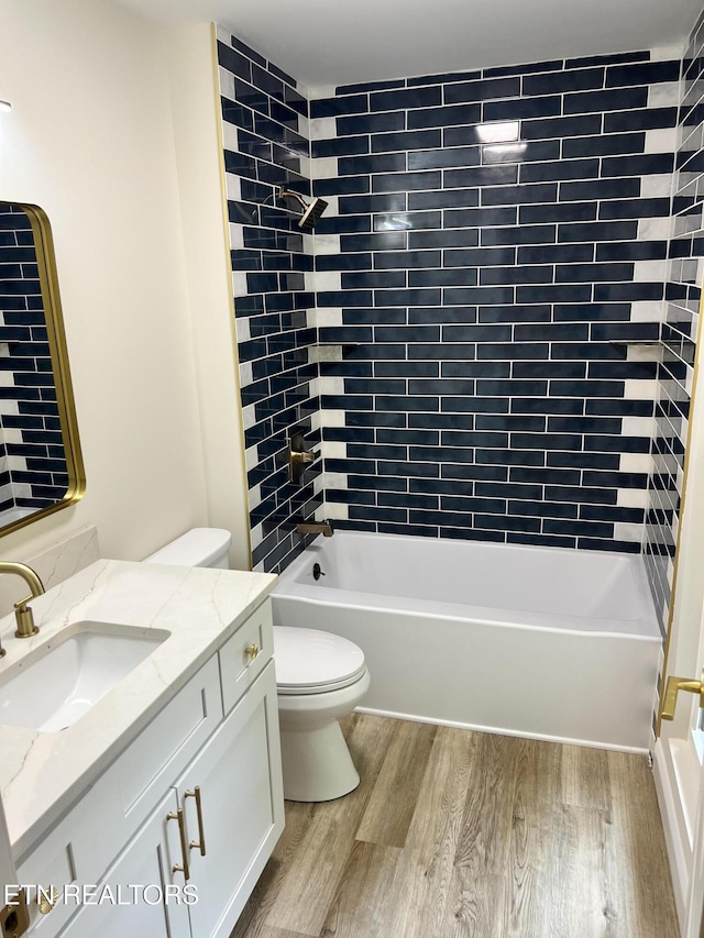 full bathroom featuring wood finished floors, toilet, vanity, and tub / shower combination