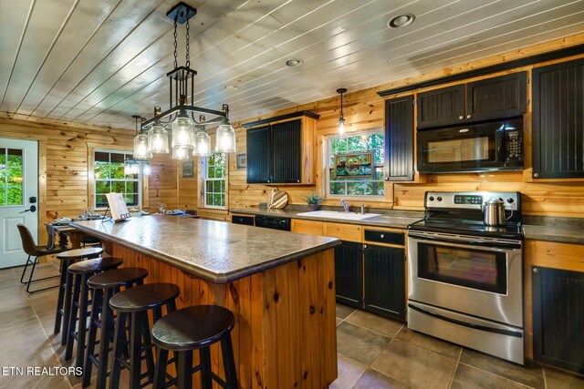 3330 Robeson Rd, Sevierville, TN 37862 - kitchen featuring black appliances, a sink, a kitchen island, a kitchen bar, and wood walls