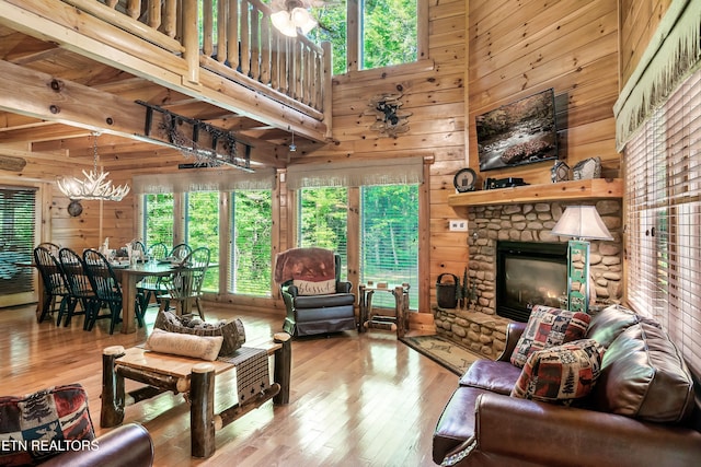 living area featuring a chandelier, healthy amount of natural light, wooden walls, hardwood / wood-style floors, and a fireplace