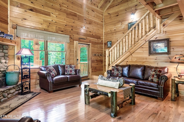 living room featuring wood walls, stairway, hardwood / wood-style flooring, and a towering ceiling