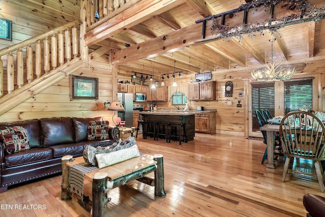 living room featuring a chandelier, wood walls, wood ceiling, light wood finished floors, and beamed ceiling