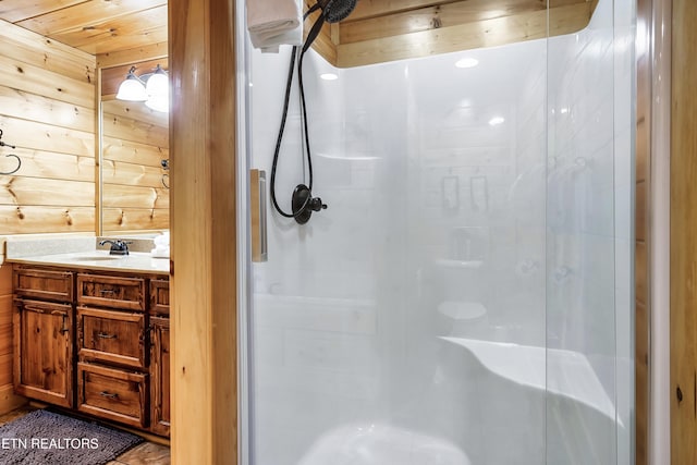 bathroom with a shower stall, vanity, and wood walls