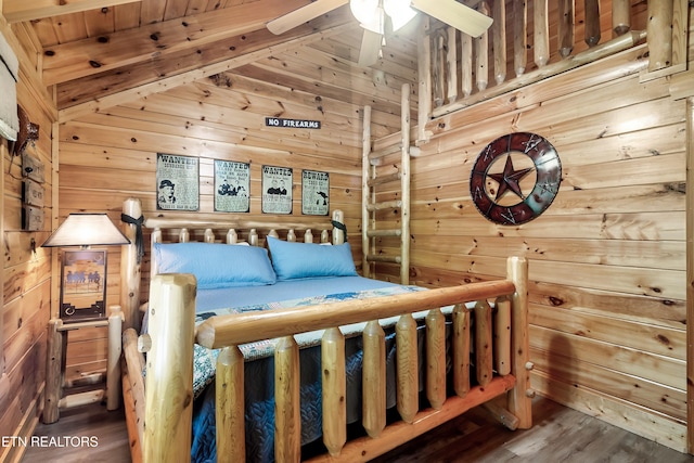 bedroom with wood walls, wood finished floors, and lofted ceiling