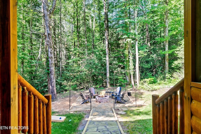 view of yard with a fire pit and a wooded view