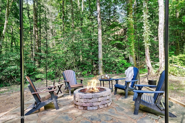 view of patio featuring a fire pit and a view of trees