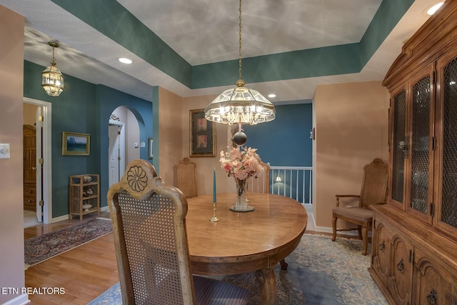 307 Okmulgee Cir, Loudon, TN 37774 - dining area featuring a chandelier, arched walkways, wood finished floors, a tray ceiling, and baseboards