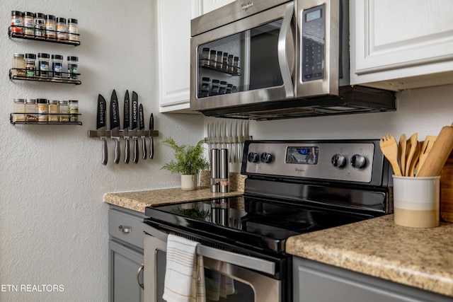 409 Melrose St, Maryville, TN 37803 - kitchen with stainless steel appliances, a textured wall, white cabinetry, and light stone countertops