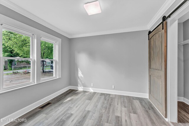 722 Southern Pkwy, Athens, TN 37303 - unfurnished bedroom with a barn door, crown molding, wood finished floors, and baseboards