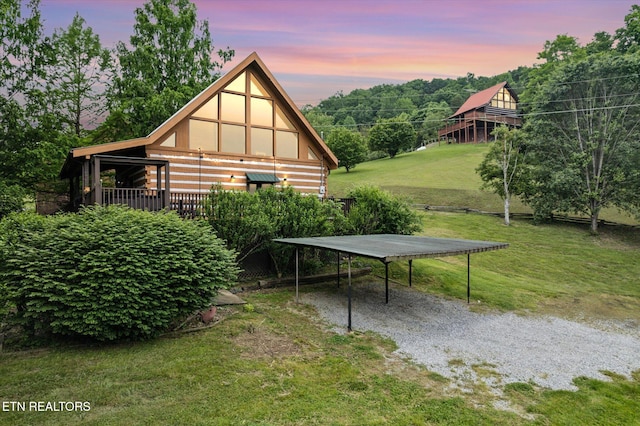 property exterior at dusk with a lawn and a detached carport