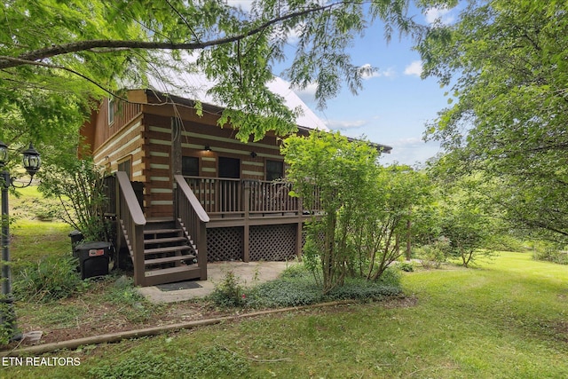 back of house featuring log siding, a yard, ceiling fan, and a deck