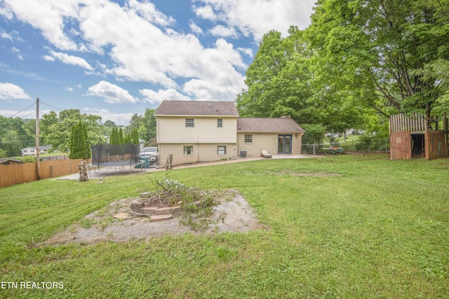 back of property with a trampoline, a patio area, an outbuilding, a shed, and a chimney