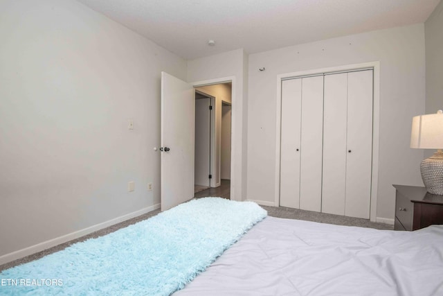 carpeted bedroom featuring a closet and baseboards