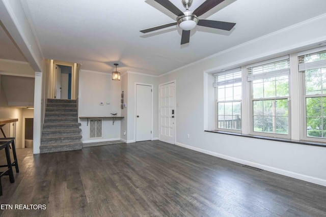 unfurnished living room featuring healthy amount of natural light, dark wood-type flooring, ornamental molding, and ceiling fan
