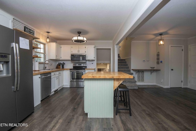 kitchen with wooden counters, appliances with stainless steel finishes, a sink, white cabinets, and dark wood finished floors