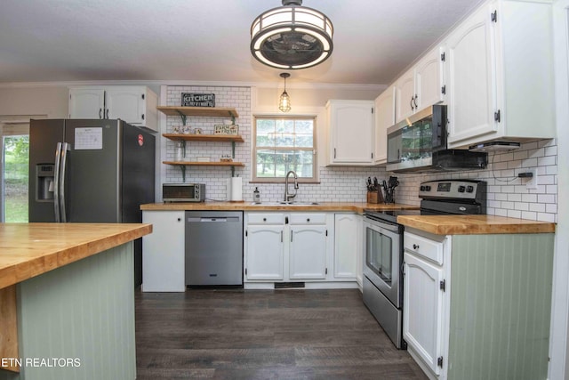 kitchen featuring appliances with stainless steel finishes, wood counters, a sink, white cabinetry, and crown molding