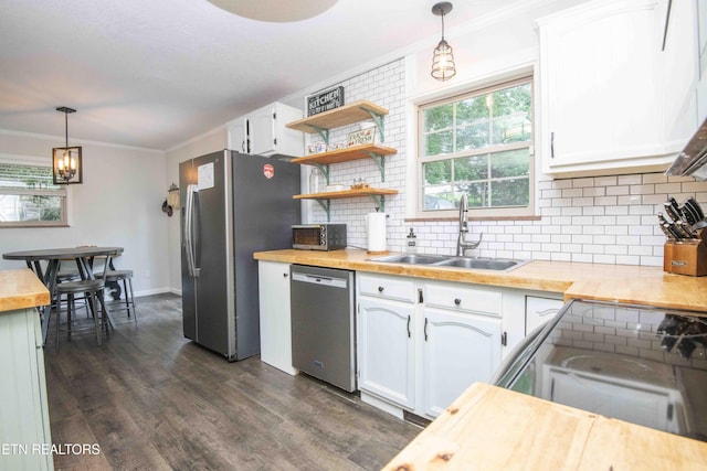 kitchen with appliances with stainless steel finishes, a sink, dark wood-type flooring, white cabinets, and butcher block countertops