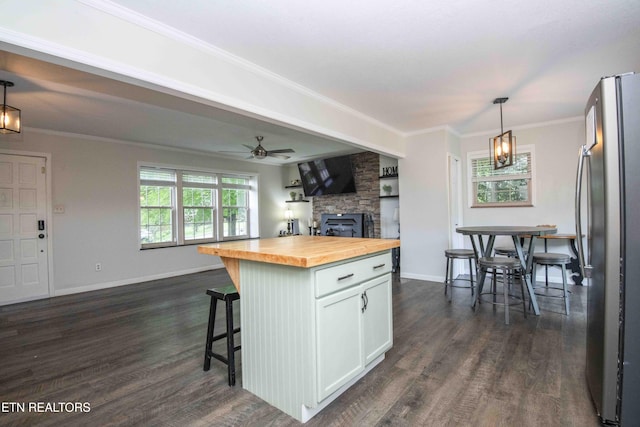 kitchen featuring butcher block countertops, freestanding refrigerator, open floor plan, white cabinets, and a kitchen breakfast bar