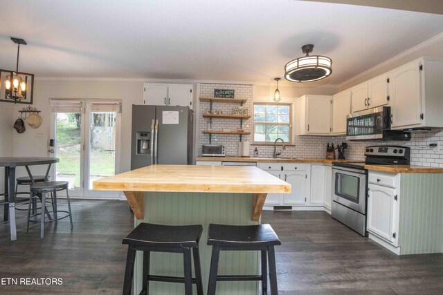 kitchen featuring appliances with stainless steel finishes, butcher block counters, white cabinets, and ornamental molding