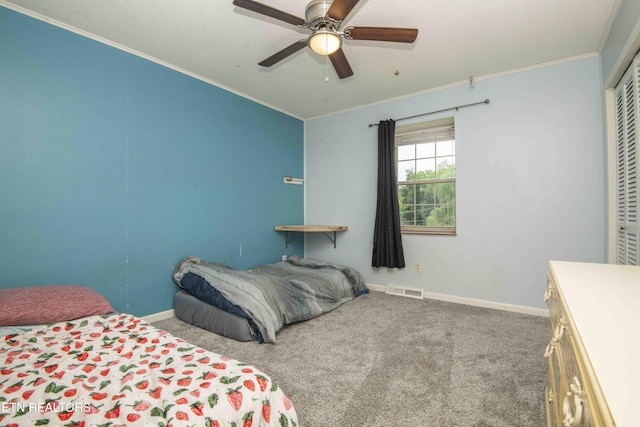 carpeted bedroom with crown molding, baseboards, a ceiling fan, and a closet