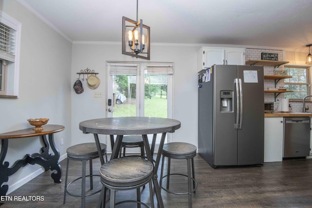 dining area featuring dark wood-type flooring, a chandelier, ornamental molding, and baseboards