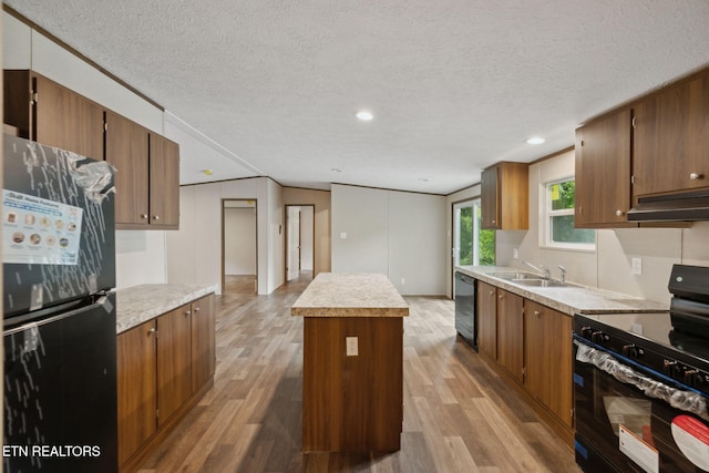 4001 Lilac Ave, Knoxville, TN 37914 - kitchen with black appliances, a kitchen island, light wood-style floors, a textured ceiling, and under cabinet range hood