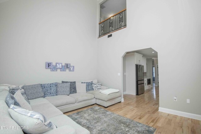 160 Brentwood Pl, Lenoir City, TN 37772 - living area with light wood-style floors, arched walkways, baseboards, and a towering ceiling