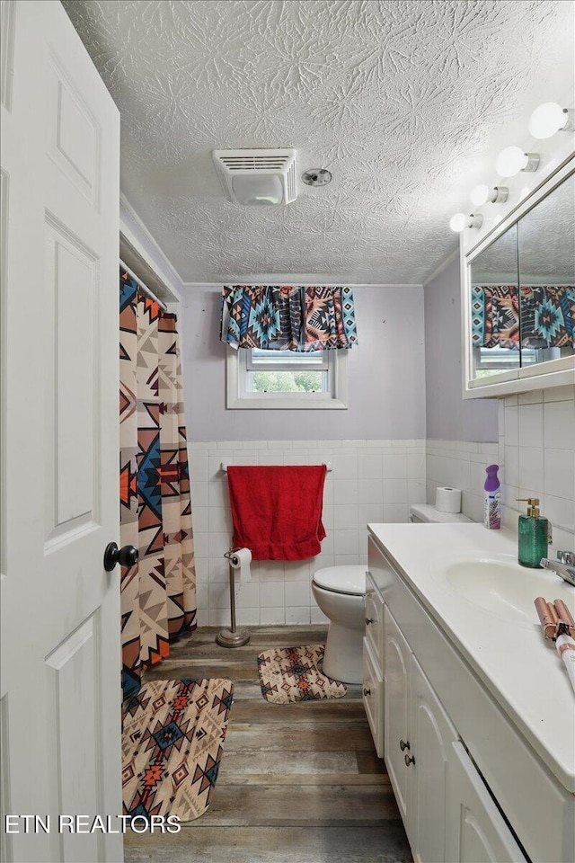 180 Stevenson Branch Rd, Middlesboro, KY 40965 - full bathroom featuring tile walls, wood finished floors, toilet, vanity, and a textured ceiling