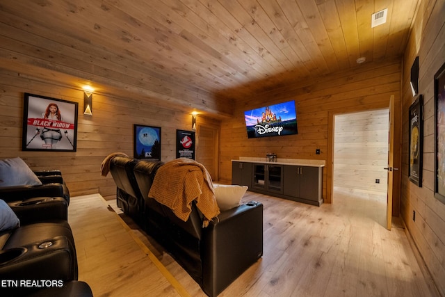 home theater room with wood walls, wood ceiling, and light wood finished floors
