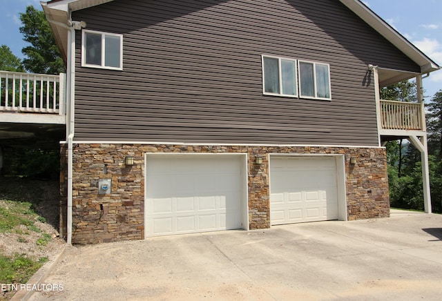 241 Oswego Rd, Jellico, TN 37762 - view of side of property featuring stone siding, an attached garage, concrete driveway, and a balcony