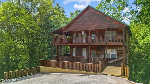 view of front of property with log exterior, uncovered parking, and a balcony