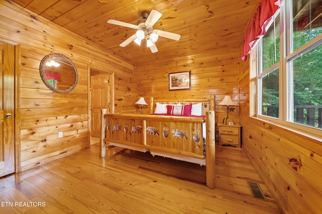 bedroom with light wood-type flooring, wooden walls, and wood ceiling