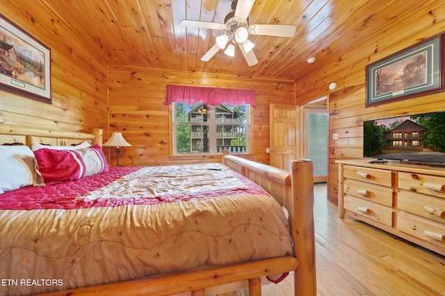 bedroom with wooden ceiling, wooden walls, and light wood-style floors