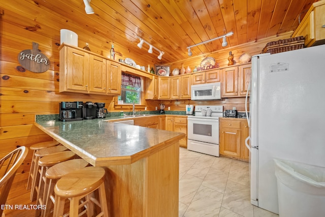 kitchen with track lighting, white appliances, a peninsula, light marble finish flooring, and a kitchen breakfast bar