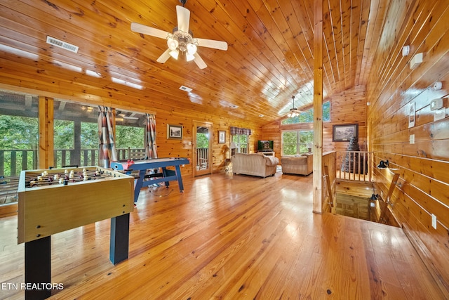 recreation room with a ceiling fan, wooden walls, hardwood / wood-style flooring, and vaulted ceiling