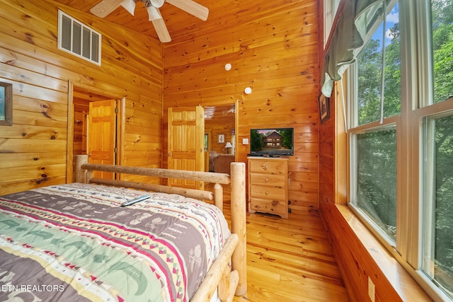 bedroom featuring wooden walls, multiple windows, and wood finished floors