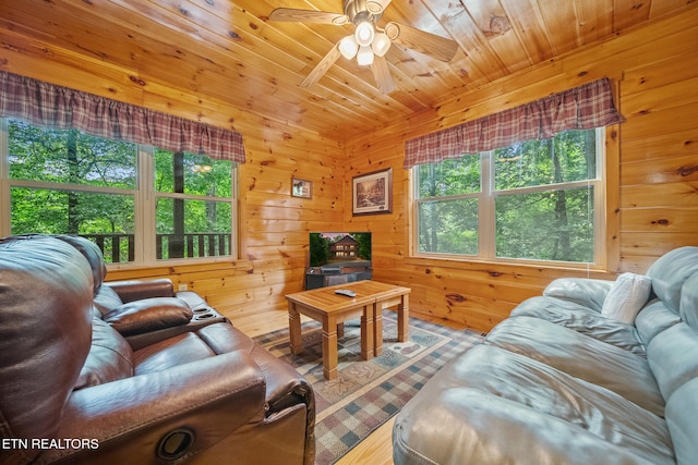 living area featuring a ceiling fan, wooden walls, wood finished floors, and wood ceiling