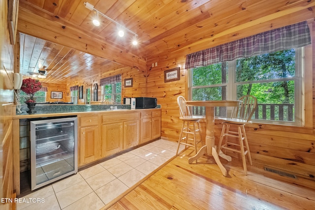 kitchen featuring wine cooler, wood ceiling, light tile patterned flooring, light brown cabinets, and wooden walls