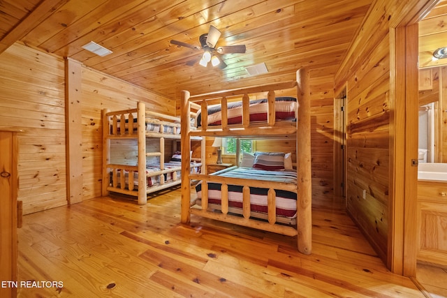 bedroom featuring light wood-type flooring, wood walls, wood ceiling, a relaxing sauna, and vaulted ceiling