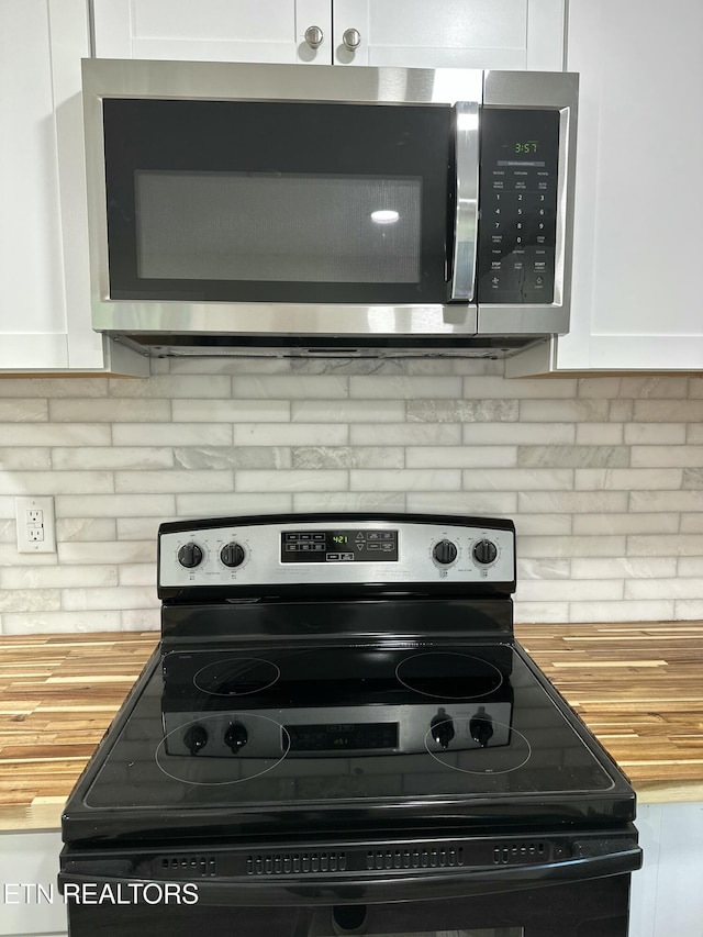 3824 Catalpa Ave, Knoxville, TN 37914 - kitchen view of black electric range, stainless steel microwave, butcher block countertops, white cabinets, and decorative backsplash