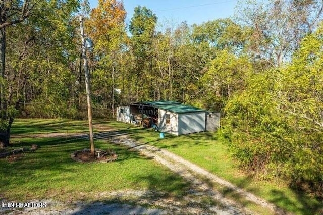 12863 Summer City Rd, Spring City, TN 37381 - view of grassy yard featuring an outdoor structure, a wooded view, a storage unit, and driveway