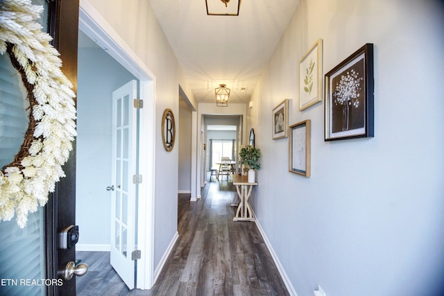 hallway featuring dark wood-style floors, baseboards, and french doors