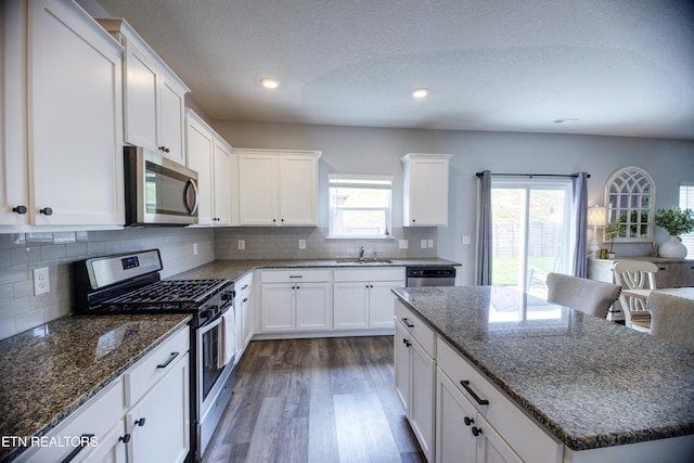 kitchen featuring stainless steel appliances, dark wood-style flooring, decorative backsplash, a center island, and white cabinetry