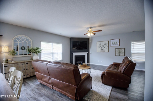 living room featuring dark wood finished floors, ceiling fan, plenty of natural light, and a textured ceiling