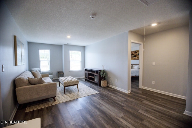 living area featuring a textured ceiling, dark wood-type flooring, attic access, baseboards, and recessed lighting
